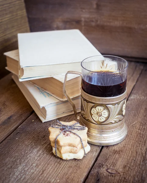 Libro, galletas y té en posavasos sobre fondo de madera —  Fotos de Stock