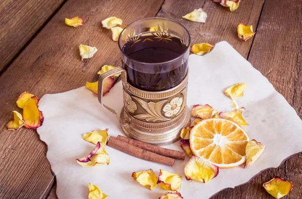 Šálek čaje v dráze, sušené pomeranče, sušených růží na dřevěné pozadí — Stock fotografie