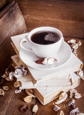 Bir fincan kahve, eski kitaplar yýðýn üzerinde duruyor. Ahşap arka plan