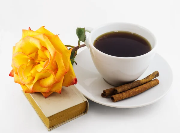 Beyaz fincan kahve, eski kitap ve beyaz zemin üzerine Sarı Gül