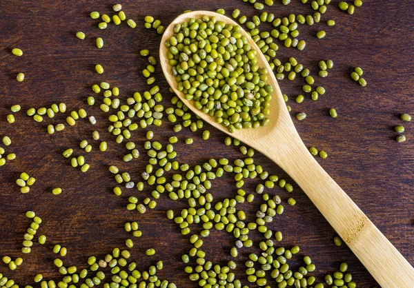 Dry uncooked mung beans in spoon on dark wooden background — Stock Photo, Image