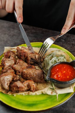 Bir lokanta, salatalık salatası ve baharatlı sosla lezzetli ızgara et yapar. Yemek saatinde restoranın rahat bir atmosferini gösteriyor..