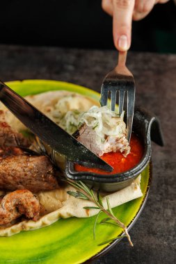 Lokanta, ellerinde çatalla Ukrayna ve Japon mutfağının çeşitli sunumlarını seviyor, rengarenk bir tabakta ızgara et ve lezzetli sosların tadını çıkarmaya hazır..