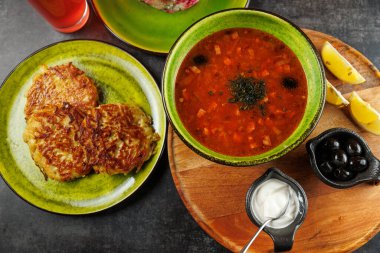 Parlak tabaklar Ukrayna borsch 'unun yanında çıtır patatesli gözleme ve kase malzeme sergiliyor. Sıradan bir yemek sahnesi kültürel mutfağın özünü yakalar..