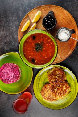 Ukrayna borş çorbası, lahana tabağı ve yeşil tabakta pembe salata ile servis edilir. Limon dilimleri, siyah zeytin, ekşi krema ve içecekler yemeğe eklenir..