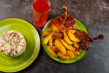 Sebze ve etten yapılmış Ukrayna salatası, kızarmış patates ve ızgara tavuğu da içerir. Bir bardak kırmızı içecek yemeği tamamlıyor, çeşitli mutfaklar sergileniyor..