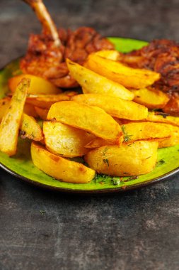 Kızarmış patateslerin yanında yeşil bir tabakta kızarmış et servis edilir. Yemek sıcak bir yemek ortamında sunuluyor, eğlenmeye hazır..