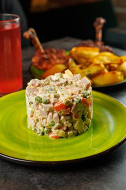 Canlı bir Ukrayna salatası kızarmış patates ve içeceğin yanında yeşil bir tabağın üzerinde oturur. Geleneksel Ukrayna ve Japon tariflerinin vurgulandığı çeşitli yemeklerin tadını çıkarın..