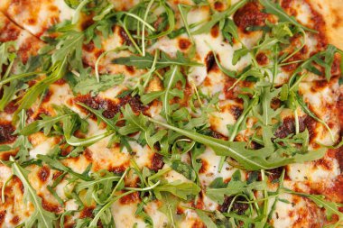 Fırından taze pizza çıkıyor, üzerinde erimiş peynir ve canlı roka yaprakları var. Bu yemek, bir toplantıda paylaşmak için mükemmel bir kombinasyon sunuyor..