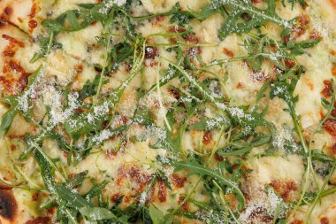 Taze bir pizza roka ve peynirle kaplanır ve mükemmel lezzet karışımı sergilenir. Akşam yemeği saatinde kalabalık bir pizzacıda bu yemeğin tadını çıkarırlar..