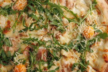 Taze bir pizza üzerine jambon, peynir ve roka ile birlikte portakal dilimleri konur. Yemek çeşitli mutfakların yer aldığı çeşitli menüleriyle tanınan bir kafeden geliyor..