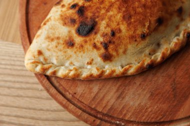 Ukrayna ve Japon mutfağından lezzetli fırınlanmış ürünler ahşap servis tahtasında sergilenir. Altın-kahverengi kabuk tatmin edici bir dokuyu gösterir ve çeşitliliğin altını çizer..