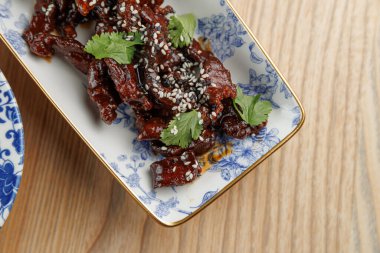 Dilimlenmiş, taze otlarla süslenmiş, susam tohumlarıyla süslenmiş, ahşap bir masada dekoratif bir kasede sunulan bir yemek. Bu yemek çeşitli mutfak geleneklerini yansıtır..