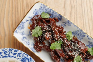 Bir yemek masasında sıralanmış çeşitli lezzet ve gelenekleri yansıtan çeşitli mutfaklarla çevrelenmiş susam tohumları, taze otlar ve pirinçten oluşan bir yemek türüdür..