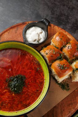 Bir tas borş otlarla süslenmiş canlı kırmızı çorba içerir. Yumuşak ekmek ruloları, küçük bir kutu ekşi kremanın yanında oturur. Tahta üzerinde, daldırmak için mükemmeldir..