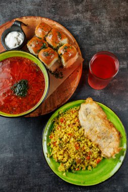 Bir restoran geleneksel yemekler sunar. Borş, sebzeli altın pirinç, ekmek ruloları ve kızarmış balık da dahil. Masadaki yemeğe renkli bir içecek eşlik eder..