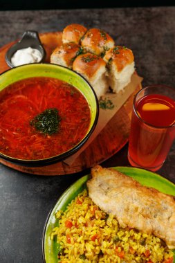 Ekmek ruloları, kızarmış balık, baharatlı pirinç ve ferahlatıcı bir içecekle birlikte bol miktarda Ukrayna borsası sergileniyor. Sıcak renkler, lokantaları doyurucu bir yemeğe davet ediyor..