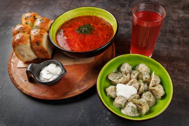 Canlı bir yemekte bir kase borş çorbası, ekşi kremalı bir tabak hamur köftesi, taze pişmiş ekmek ve ferahlatıcı bir meyve suyu sergilenir. Kurulumda Doğu Avrupa aşçılık gelenekleri vurgulanıyor.