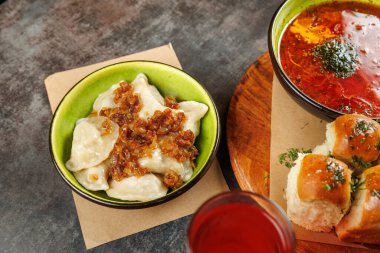 Geleneksel yemeklerden oluşan bir seçimde Ukrayna mutfağı ve Japon mutfağı sergileniyor. Kızarmış soğanla kaplı hamur köfteleri zengin bir çorba ve yumuşak ekmek rulolarının yanında oturur. Canlı renkler yiyeceği vurguluyor..