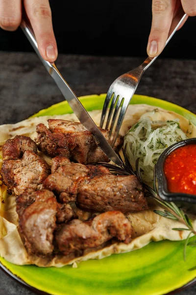 Biri taze salata ve baharatlı sosla birlikte kızarmış eti ekmeğin üzerinde dilimliyor. Bu yemek, Ukrayna mutfağının canlı bir yemek atmosferinde tadını çıkaran lezzetlerini ön plana çıkarıyor..