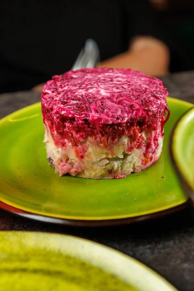 Yeşil bir tabakta sunulan pancar ve diğer sebzelerin yer aldığı katmanlı tabağın yakın çekimi. Bu Ukrayna yemeği taze malzeme ve koyu renkleri vurguluyor.