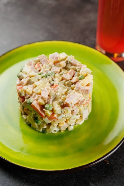 Dilimlenmiş sebze ve etten yapılmış renkli bir salata yeşil bir tabakta servis edilir. Tabağın yanına ferahlatıcı bir içecek konur. Bu yemek çeşitli mutfaksal tatlar sunar..