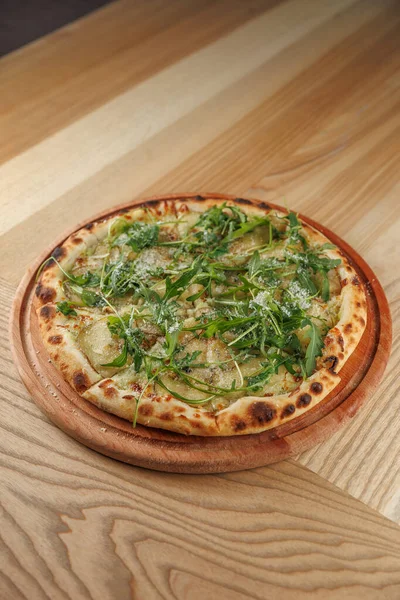 Düz ekmekte taze yeşillik ve otların karışımı var. Hepsi düzgünce yerleştirilmiş. Tabak detaylarını vurgulayan yuvarlak ahşap bir tahtada servis edilir..