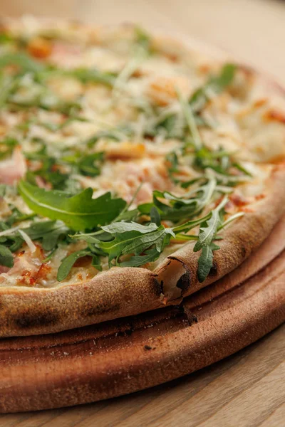 Taze pişmiş pizza ahşap bir tahtaya konur. Erimiş peynirle kaplanmış ve üzeri canlı roka ile kaplı bir kabuk içeriyor. Sıcak, davetkar yemek paylaşmak için mükemmel..