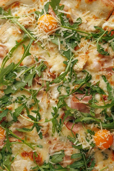 Taze bir pizza roka, peynir ve portakallı domatesle kaplıdır. İnsanlar akşam yemeği için bir restoranda masanın etrafında toplanıyorlar. Atmosfer canlı ve parlak..