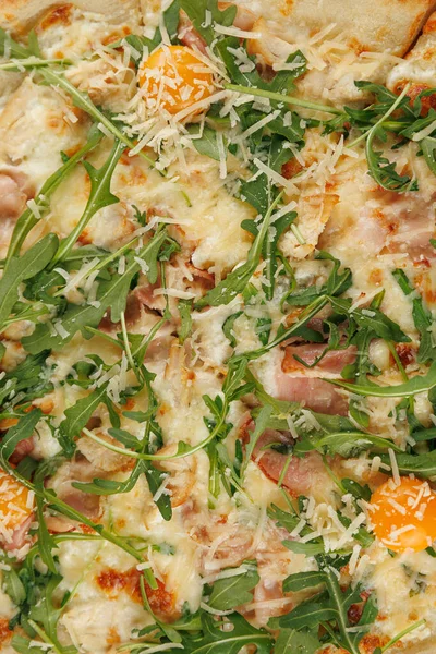 Pizzada taze roka, erimiş peynir ve çeşitli malzemeler var. Arkadaşlarla ve ailelerle paylaşmak için mükemmel bir ortam..