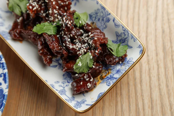 Dekoratif bir tabakta proteinler ve süslemeler yer alır. Sunumda çeşitli uluslararası mutfak etkileri sergileniyor ve bu da keyif vermeye teşvik ediyor..