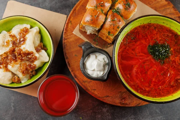 Bir masada çeşitli geleneksel Ukrayna yemekleri sergileniyor. Bunlar arasında bitkilerle servis edilen canlı borş, soğanlı kremalı hamur tatlısı ve taze ekmek ruloları yer alıyor..