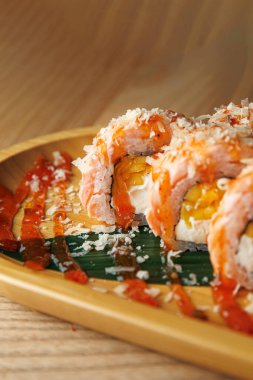 Suşi hamuru ahşap bir tabakta güzelce sıralanmış. Sos ve malzemelerden gelen parlak renkler sunumu güçlendirir. Bu yemek Japon mutfağının özünü yakalar..