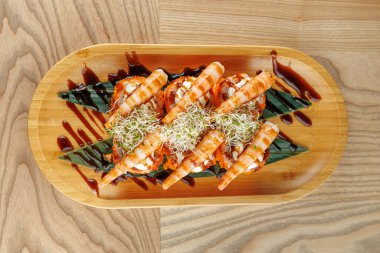 Tahta bir tabakta karides ve lahanayla kaplı bir suşi seçimi vardır. Canlı renkler ve dikkatli düzenleme çeşitli aroma ve dokular sergiliyor. Bu yemek Japon mutfağını ön plana çıkarıyor..