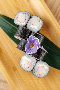 Yengeç ve pirinçle dolu suşi ruloları bambu tabakta düzenlenir. Rengarenk bir çiçek yemeğe bir tutam süs katar, aromalar ve dokular harmanlanır..
