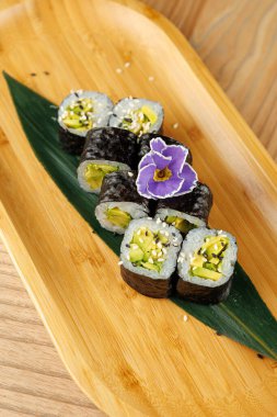 Sebze turşusuyla dolu suşi rulolarının ve susam tohumlarının ve bambu tabakta bir çiçeğin tadını çıkarıyorum. Öğle ya da akşam yemeği için mükemmel..