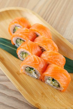 Sebzelerle dolu suşi ruloları ve canlı somon dilimleri ahşap bir tabakta güzelce düzenlenir. Bu yemek ya da paylaşılan yemek deneyimi için mükemmel..