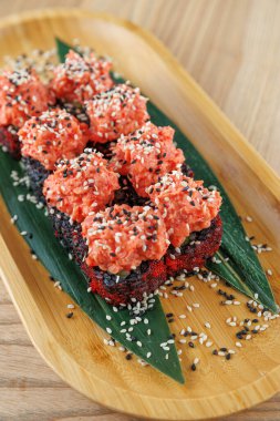 Canlı balık ve pirinçten yapılmış bir suşi gösterisi bambu tabakta düzenlenmiş. Suşi susam tohumları ve yeşil yapraklar içeriyor..