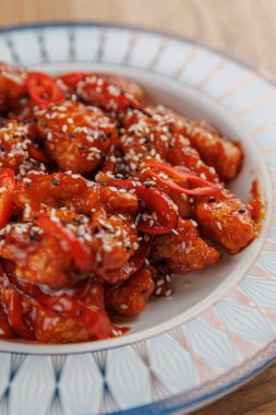 Bu yemek, dilimlenmiş kırmızı biberlerle süslenmiş ve susam tohumlarıyla süslenmiş, zengin bir sosla kaplanmış tatlı ve baharatlı tavuk parçaları içeriyor. Her yemek için mükemmel..