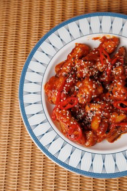 Kırmızı soslu sebzeli kızarmış karides tabağı. Dilimlenmiş dolmalık biber ve üzerine serpiştirilmiş susam tohumları, canlı bir yemek yaratıyor..