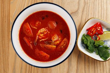 Bir kase baharatlı çorba zengin bir kırmızı et suyunda karides, domates ve çeşitli otlar içerir. Taze limon, acı biber ve kişniş içerir..