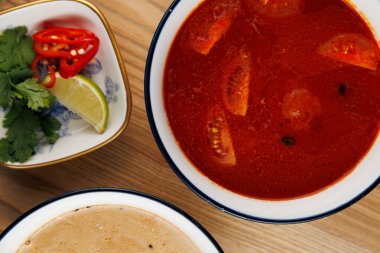 İki kase yemek geleneksel Ukrayna borsası ve Japon eriştesi sergileniyor, otlar, biberler ve ahşap bir masada limon dilimleri ile süslenmiş..