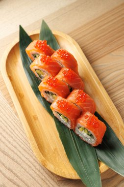 Sebze ve balıklarla dolu renkli suşi ruloları bambu tabakta oturur. Tabakta geleneksel Japon mutfağını vurgulayan somon yumurtası yer alıyor..