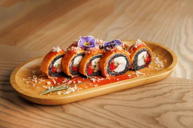 Ahşap bir tabakta sergilenen suşi ruloları. Her rulo çeşitli dolgu ve malzemeler içeriyor. Ayar canlı renkler ve taze malzemeler vurguluyor.