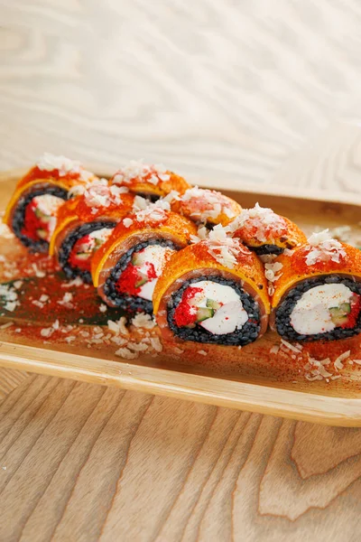 Taze yapılmış suşi ruloları ahşap bir tabakta güzelce düzenlenir. Ekmekte balık, sebze ve pirinç gibi canlı malzemeler yer alıyor. Restoranda paylaşmak için mükemmel..