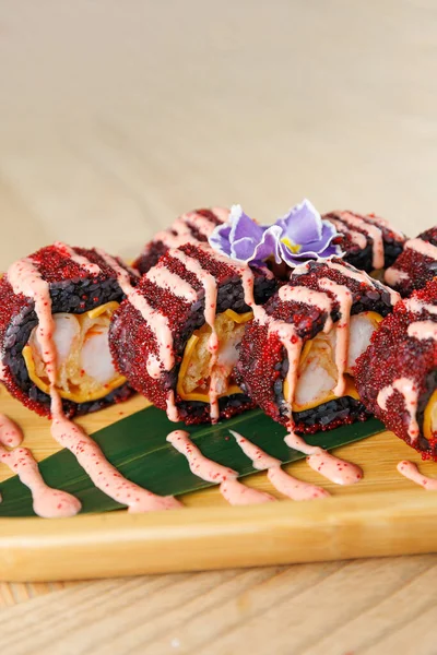 Suşi dürümleri ahşap bir tepside, canlı malzemeler ve renkli çiselemelerle güzelce düzenlenir. Bu yemek sıradan bir lokantada popüler bir seçim..