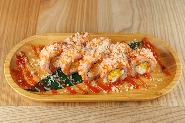 Ahşap bir tabakta çeşitli suşi dürümleri sos ve peynirle süslenir. Ayarlar gündelik, basit ahşap bir arka planı ve canlı renkleri var..