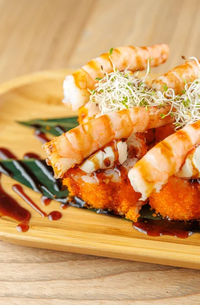 Canlı bir suşi gösterisi yemeği çıtır çıtır pirinçli, lahanalı ve soslu karides pişirdi. Tahta tabaka sunumu güçlendirir.