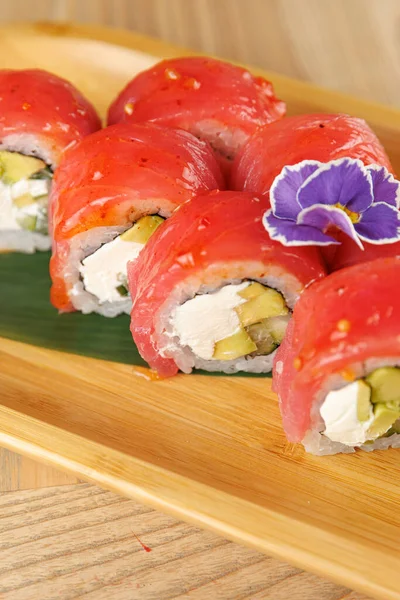 Taze suşi ruloları bambu tabağına konur. Her rulo ton balığı, krem peynir ve salatalıktan yapılır. Bir çiçek tabağı süsleyip sunumunu geliştirir..