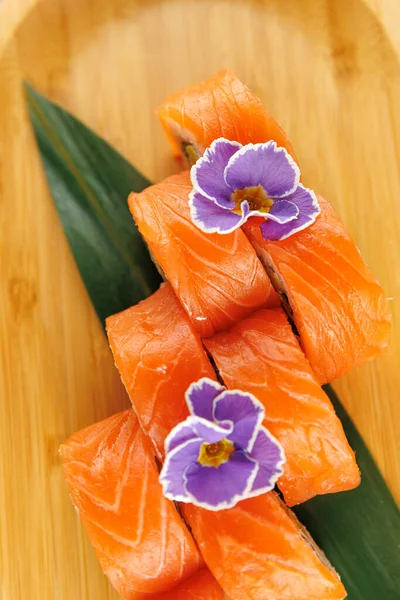 Somon balığı parçaları ahşap bir tabakta güzelce düzenlenir. Her parça mor çiçeklerle süslenmiş, Japon mutfağındaki detaylara dikkat çekiyor..